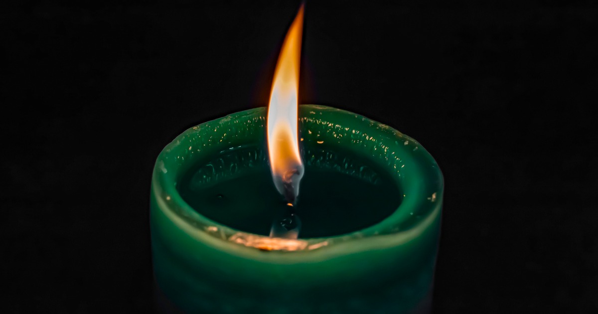 Green Candle Lit In Darkness